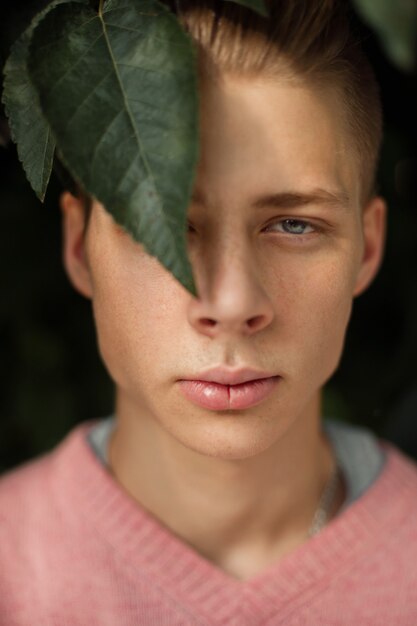 Retrato natural de un apuesto joven con pecas con hojas verdes