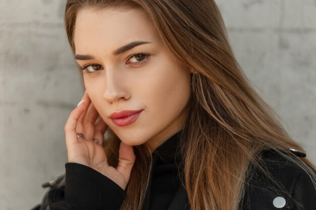 Retrato natural fresco de mujer de una hermosa joven con piel facial clara y maquillaje en ropa de moda mirando a la cámara