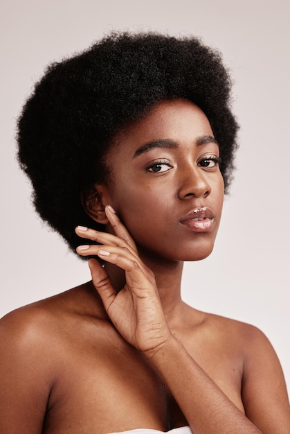 Foto retrato natural ou cuidados com a pele e uma mulher negra modelo no estúdio em um fundo cinza com cabelo afro cosméticos para a pele e beleza com uma mulher jovem e atraente posando em ambientes fechados para saúde ou bem-estar
