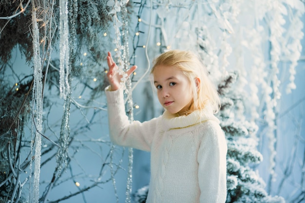 El retrato de la Navidad del estudio interior de la muchacha rubia feliz del niño, invierno nevoso adornó el árbol