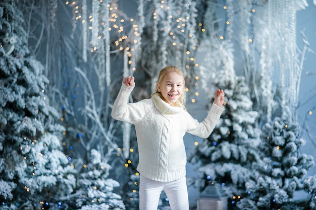 El retrato de la Navidad del estudio interior de la muchacha rubia feliz del niño, invierno nevoso adornó el árbol