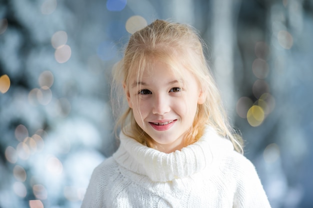 El retrato de la Navidad del estudio ndoor rubio feliz de la muchacha del niño, invierno nevoso adornó el árbol