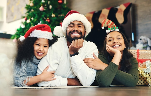 Retrato de Navidad y familia niños y padres en el salón celebración de invierno y amor cuidado y felicidad juntos Familia feliz niña y niño celebran vacaciones festivas sombreros de santa o sala de estar