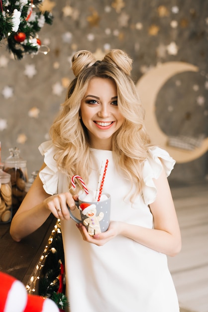 Retrato de Navidad de una hermosa niña con una taza roja en el fondo de un bar de Navidad. Año nuevo y concepto navideño