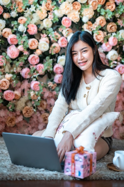 Retrato de negocios independientes hermosa sonrisa positiva joven mujer asiática en línea trabajando con una computadora portátil en casa en la sala de estar interior Decoración durante las vacaciones de Navidad y Año Nuevo