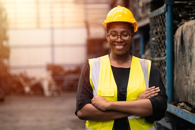 Retrato negro trabajadora africana inteligente de pie feliz sonriendo en el lugar de trabajo de la industria fabril