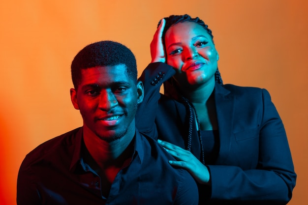 Retrato de neón oscuro de joven afroamericano y mujer. Luz roja y azul.