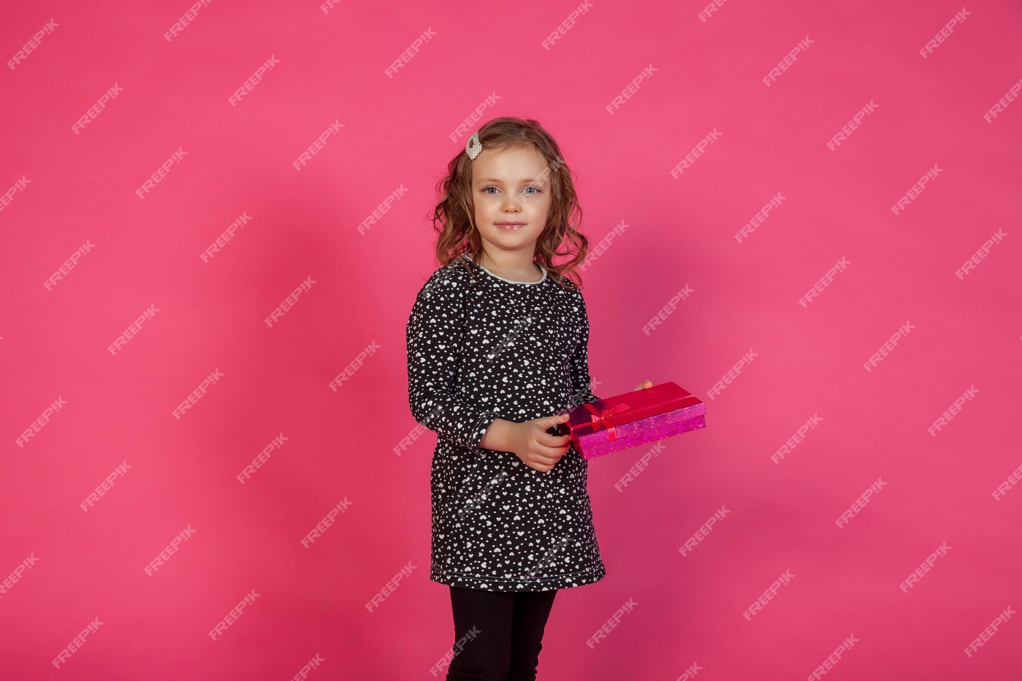 Linda niña de 5-6 años con elegante vestido rosa sentado en la