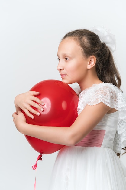 Retrato de niña abrazando globo rojo con ambas manos poner la barbilla en la bola mirando hacia el lado en blanco