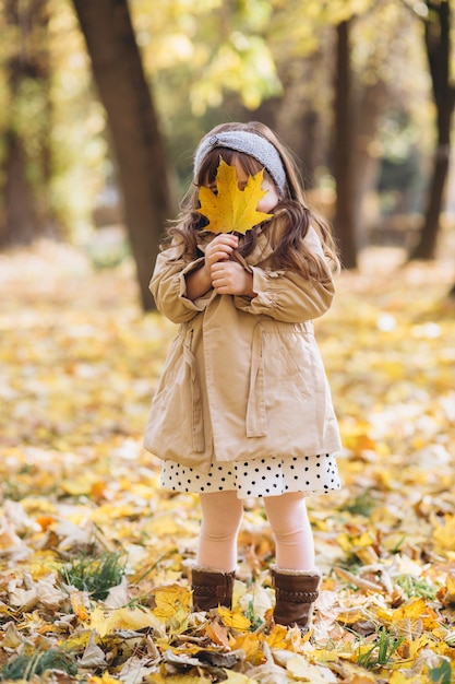 Foto retrato de niña con un abrigo beige camina en el parque de otoño