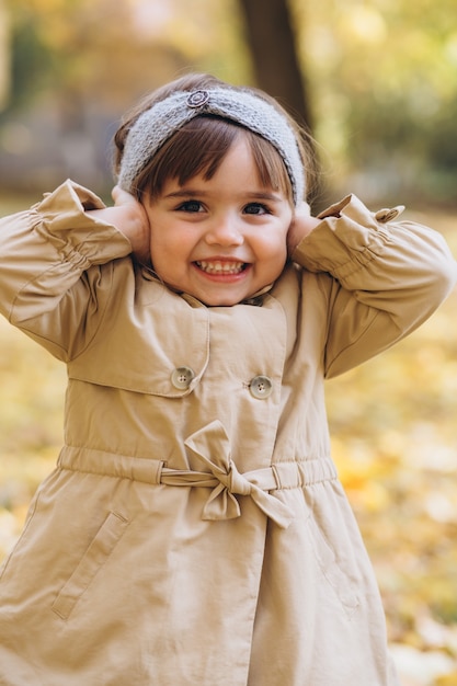 Retrato de niña con un abrigo beige camina en el parque de otoño