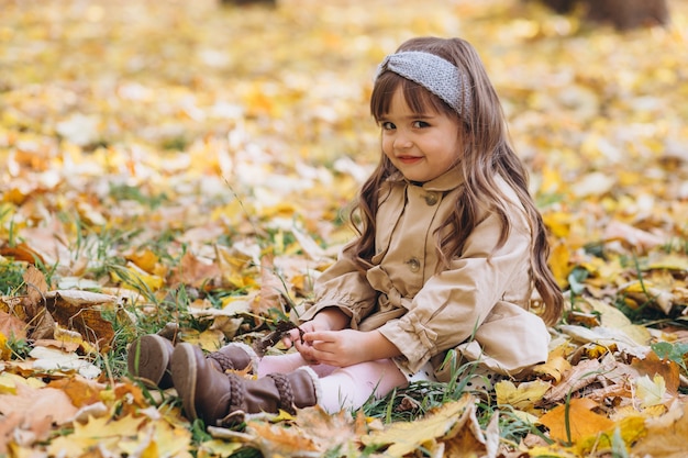 Retrato de niña con un abrigo beige camina en el parque de otoño