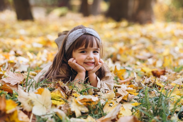 Retrato de niña con un abrigo beige camina en el parque de otoño