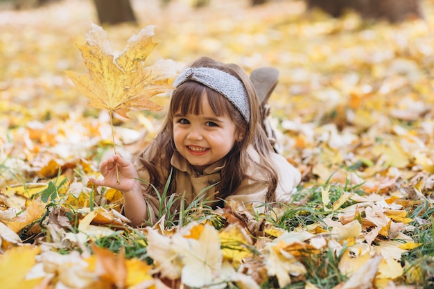 Retrato de niña con un abrigo beige camina en el parque de otoño