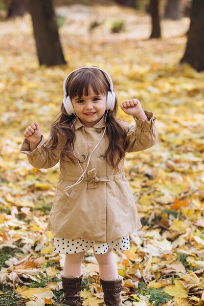 Retrato de niña con un abrigo beige camina en el parque de otoño