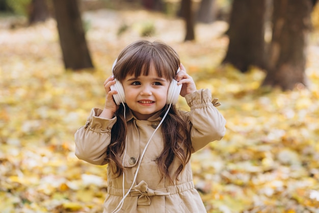 Retrato de niña con un abrigo beige camina en el parque de otoño