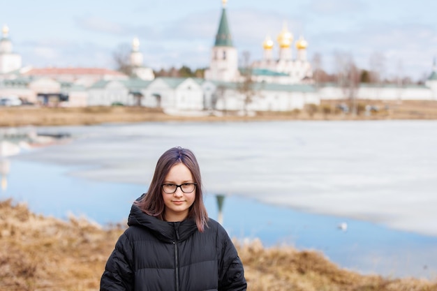 Retrato de una niña adolescente en el contexto de vistas antiguas y un paisaje primaveral que se derrite de la nieve del lago