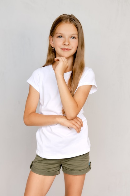 Retrato de niña adolescente positiva con la mano cerca de la barbilla