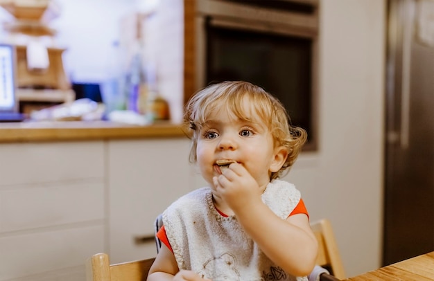 Retrato de una niña adorable comiendo en una mesa en casa