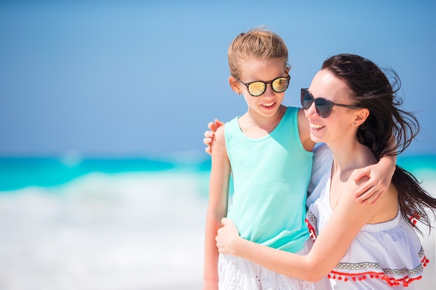 Retrato de niña adorable y joven madre en playa tropical