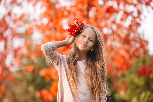 Retrato de niña adorable con ramo de hojas amarillas en otoño