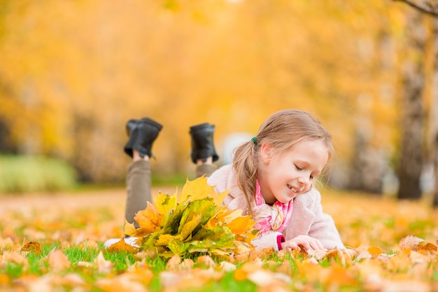 Retrato de niña adorable con ramo de hojas amarillas en otoño