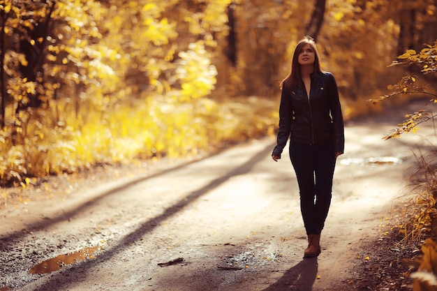 Retrato de niña adulta joven en el parque de otoño fondo de hojas amarillas