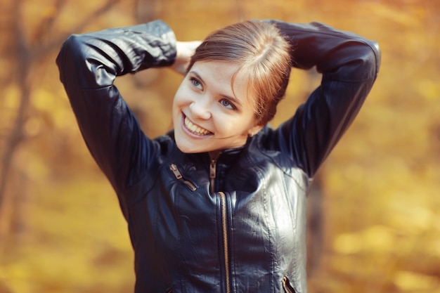 Retrato de niña adulta joven en el parque de otoño fondo de hojas amarillas