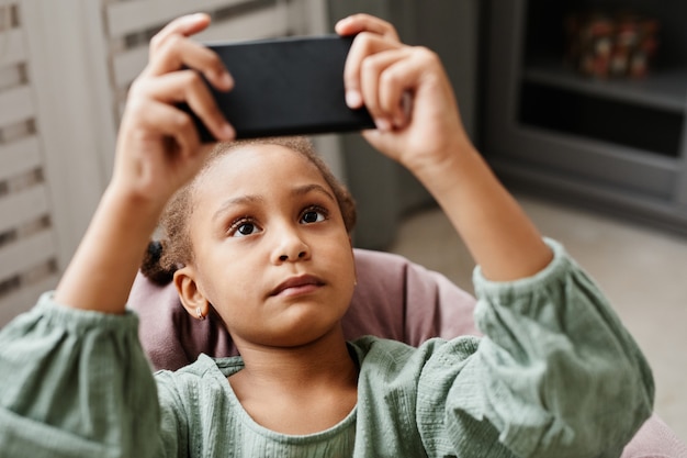 Retrato de niña afroamericana de cerca con smartphone en casa espacio de copia