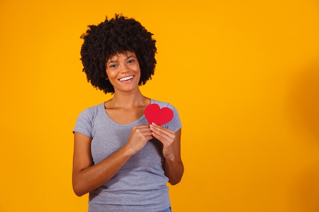 Retrato de niña aislada sosteniendo un corazón de papel en amarillo