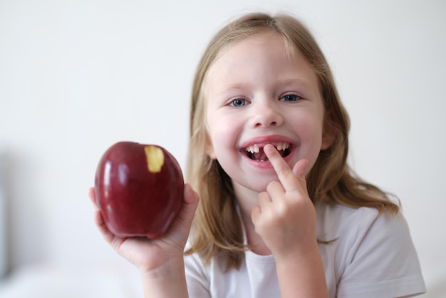 Retrato de niña alegre sin dientes tiene manzana