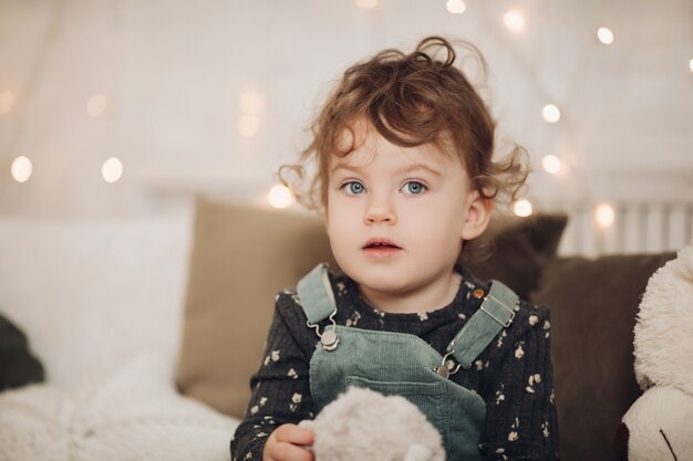Retrato de niña alegre se relaja en un ambiente navideño con luces de fondo