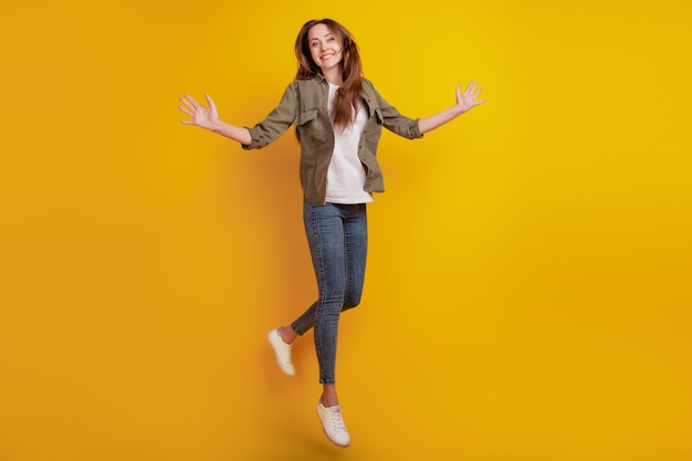 Retrato de niña alegre saltando aislado sobre fondo amarillo