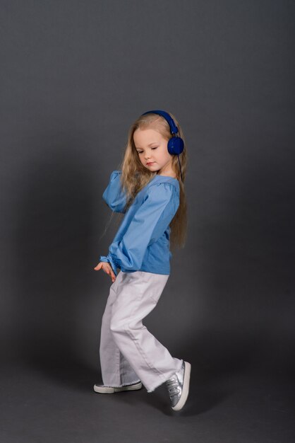 Retrato de una niña alegre saltando y bailando sobre un fondo de estudio