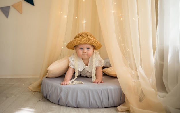 Foto retrato de una niña alegre sentada en un colchón bajo un dosel y gateando