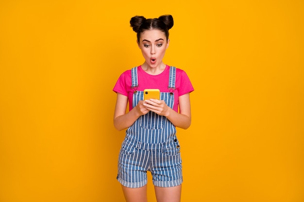 Retrato de niña alegre usa conexión inalámbrica de teléfono celular sobre fondo amarillo