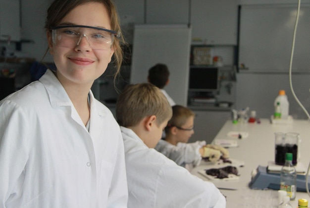 Retrato de una niña con amigos en el laboratorio de biotecnología de la escuela