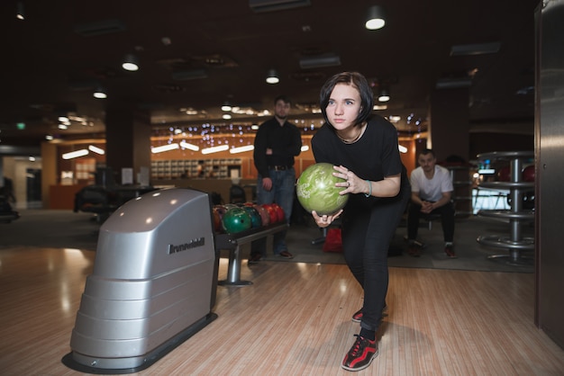 Retrato de una niña antes de lanzar una bola para bolos en el sketch. Niña juega bolos.