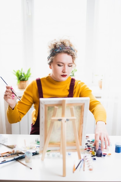 Retrato de una niña artista que crea una pintura en casa.