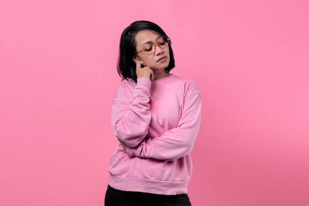 Retrato de niña asiática con chaqueta rosa mirando pensativo, triste e infeliz