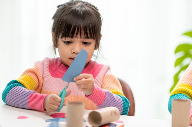 Retrato de una niña asiática cortando un papel en actividades en la clase de bricolaje en papel cortado SchoolScissors