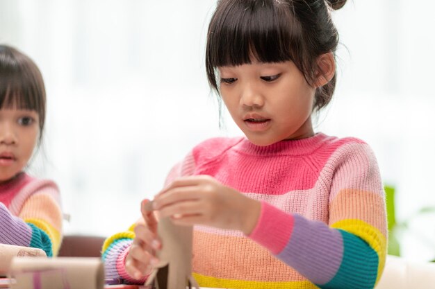 Retrato de una niña asiática cortando un papel en actividades en la clase de bricolaje en papel cortado SchoolScissors