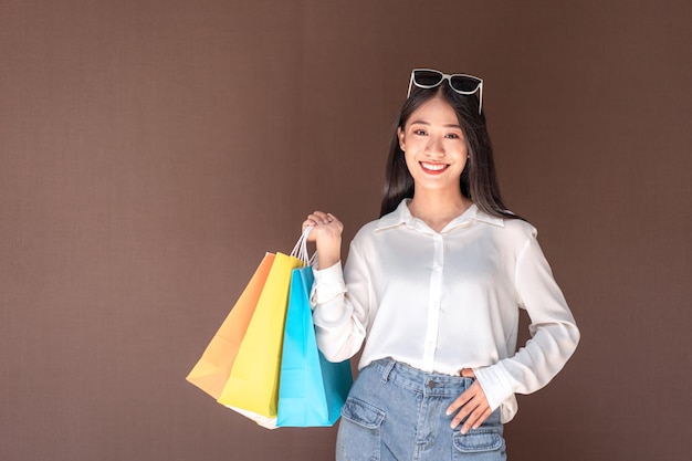 Retrato de niña asiática emocionada hermosa niña con gafas de sol feliz sonriendo con bolsas de compras disfrutando de expresión relajada de compras, compras de emociones positivas, concepto de estilo de vida.