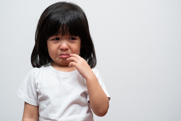 Retrato de niña asiática enojada triste y llorar sobre fondo blanco aislado La emoción de un niño