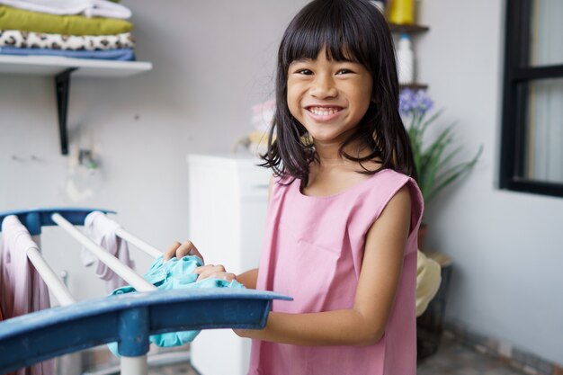 Retrato de niña asiática feliz lavando ropa en casa