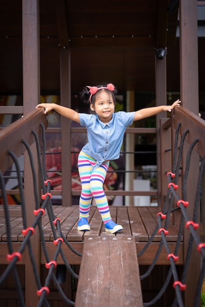 Retrato de niña asiática en el puente en el patio de recreo