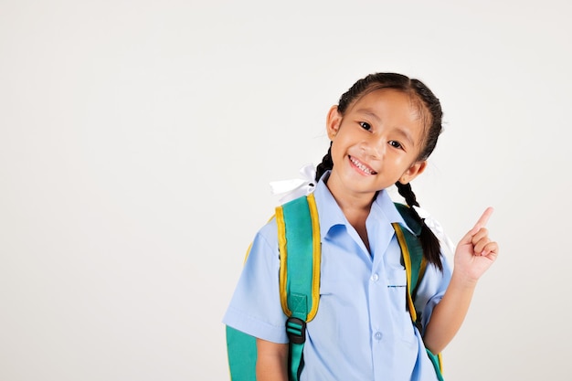 Retrato de una niña asiática sonriente en el jardín de infantes con el bolso apuntando con el dedo al estudio de copia de espacio