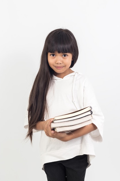 Retrato de niña asiática sosteniendo un libro sobre fondo blanco.