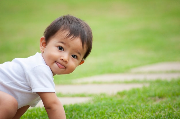 Retrato de una niña de aspecto asiático de 1 año. Escena divertida, mostrando la lengua. Escena al aire libre. Copia espacio