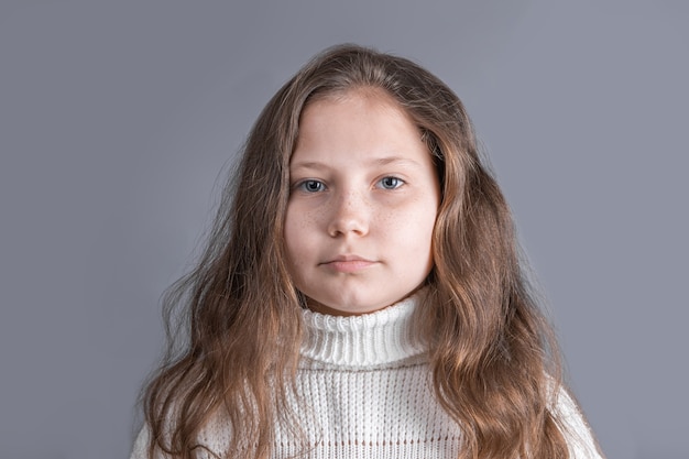 Retrato de una niña atractiva joven con cabello largo y rubio que fluye en un suéter blanco sonriendo Lugar para el texto. Copie el espacio.